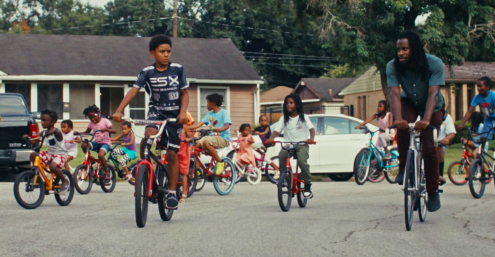 Omari Cato riding a BMX bike with children in a neighborhood, teaching and inspiring young riders.
